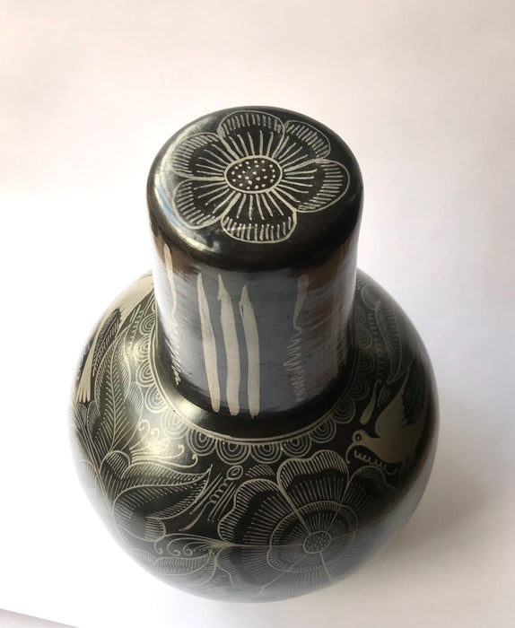 Mexico 1492: The black “cántaro” (pitcher), hand made out of clay, hand painted with birds, flowers and leaves, and burnished to shine. Accompanied by a matching glass. Used for storing liquids, like water or wine.   “Cántaro” is a precious piece in every Mexican home, and a favorite way to store water. It is believed that water stays cool in a “cántaro” even on a hottest day.